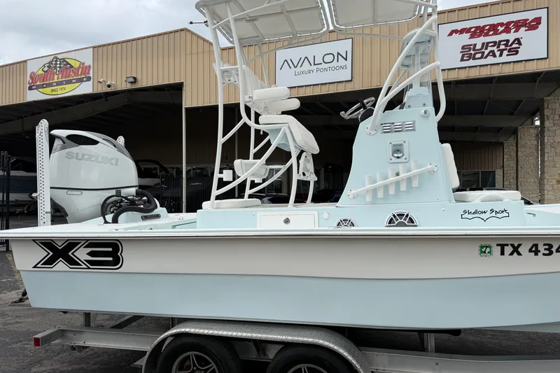 Slide: The Image of 2023 Shallow Sport 25 X3 boat on trailer, displayed outside dealership. - 4
