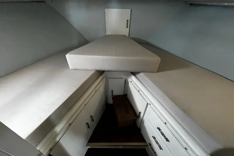 Slide: The Image of 1974 Tollycraft 37 Convertible cabin interior with white bedding and storage cabinets. - 38