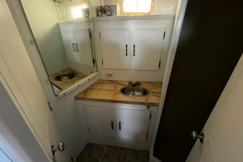 Slide: The Image of 1974 Tollycraft 37 Convertible bathroom with sink, mirror, and storage cabinets. - 36