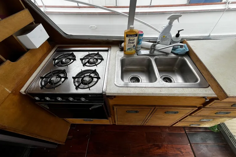 Slide: The Image of 1974 Tollycraft 37 Convertible kitchen with stove, double sink, and cleaning supplies. - 20
