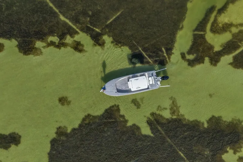 Slide: The Image of Aerial view of 2023 Haynie 25 Magnum boat navigating through shallow, algae-filled waters. - 14