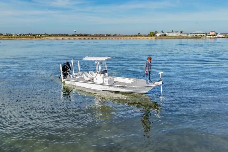 Slide: The Image of 2023 Haynie 25 Magnum boat on calm water with a person standing on deck. - 2