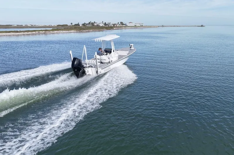 Slide: The Image of 2023 Haynie 25 Magnum boat cruising on calm waters near the shoreline. - 7