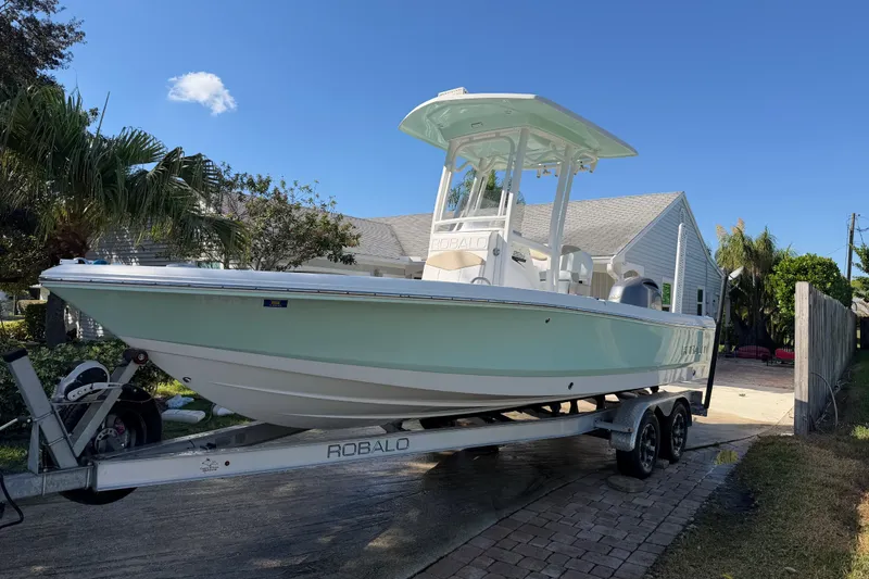 The Image of 2018 Robalo 226 Cayman boat on trailer in residential driveway, sunny day. - 0