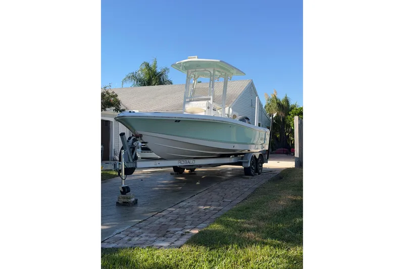 Slide: The Image of 2018 Robalo 226 Cayman boat on trailer in driveway, clear blue sky background. - 2