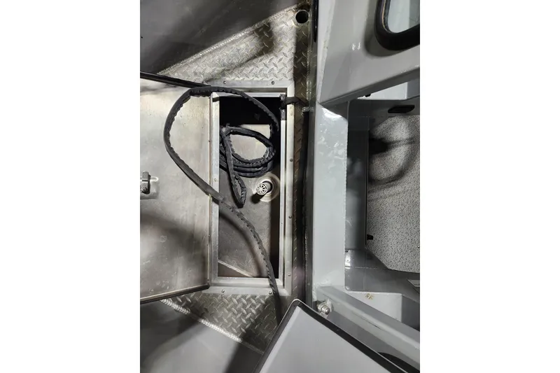 Slide: The Image of 2024 Hewescraft 180 Sportsman interior storage compartment with coiled rope and metal flooring. - 10