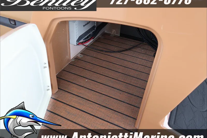 Slide: The Image of 2026 Bentley Pontoons Elite 223 Swingback storage compartment with wood-textured flooring. - 26