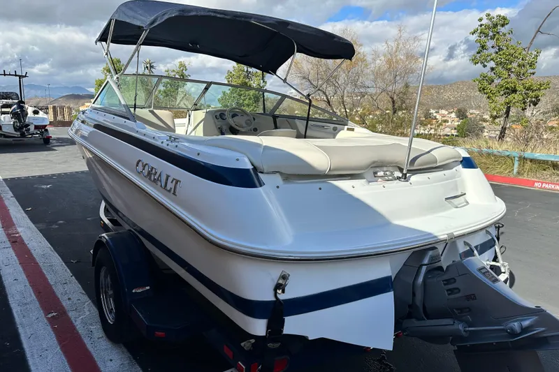Slide: The Image of 1997 Cobalt 190 boat with blue canopy, parked on a trailer, against a brick wall. - 5
