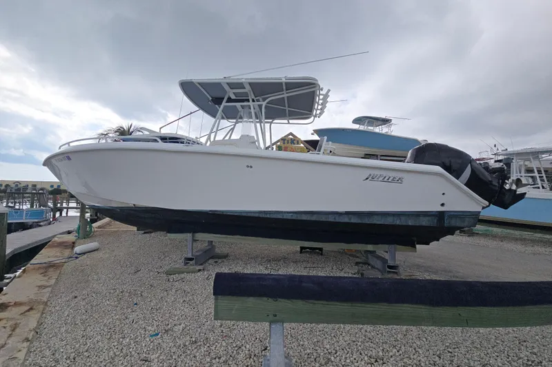 The Image of 2004 Jupiter boat on dry dock, white hull, overcast sky background. - 1