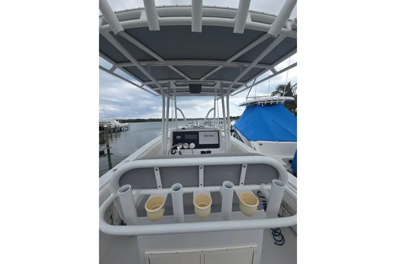 Slide: The Image of 2004 Jupiter boat console with rod holders and canopy, docked by the water. - 10