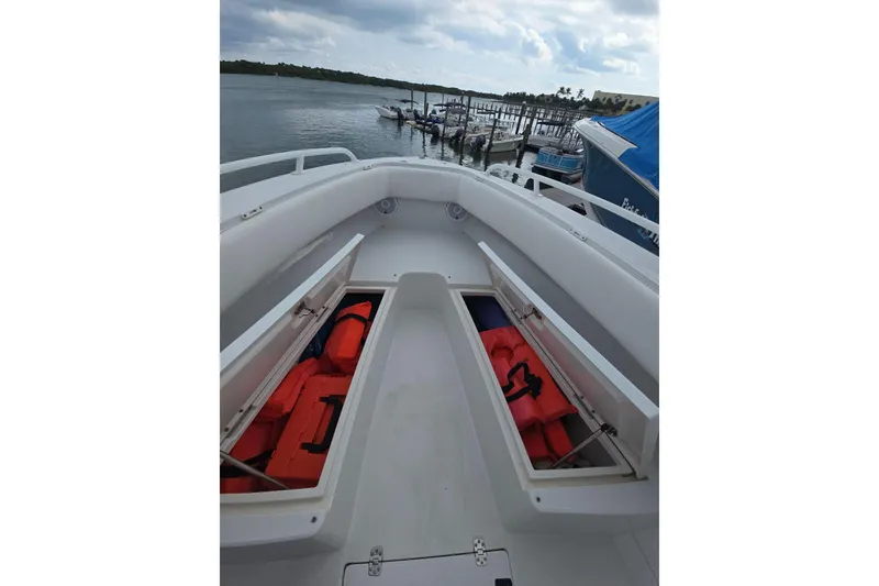 Slide: The Image of 2004 Jupiter boat with open storage compartments and life jackets, docked by the water. - 8