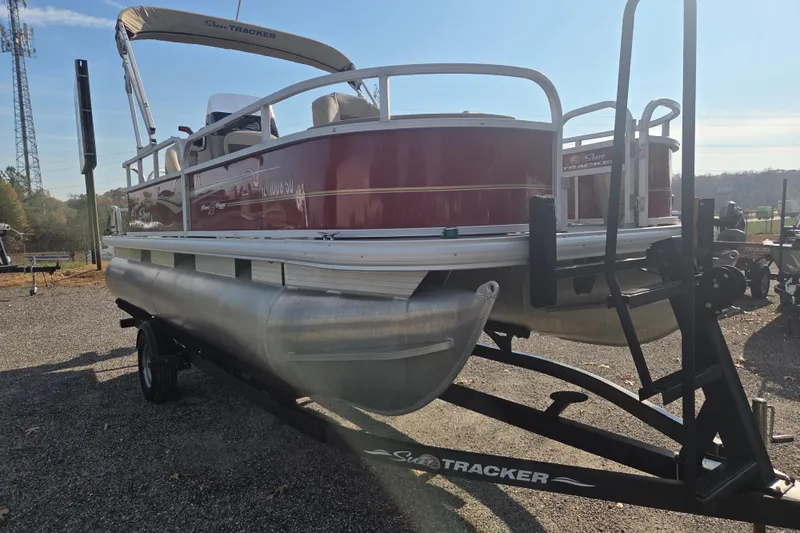 Slide: The Image of 2021 Sun Tracker Bass Buggy 18 DLX pontoon boat on trailer, parked outdoors. - 2