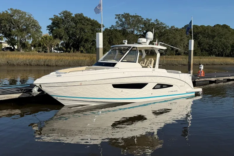 The Image of 2019 Regal 33 SAV boat docked on calm water with trees in the background. - 0