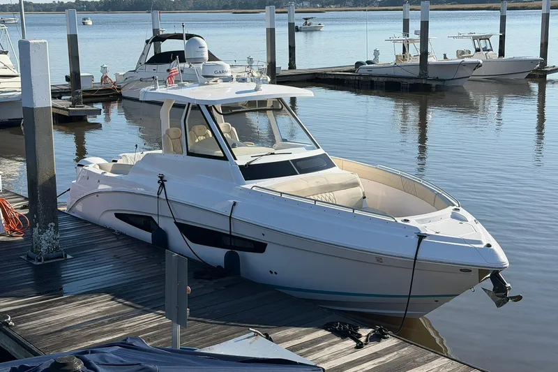 Slide: The Image of 2019 Regal 33 SAV boat docked at a marina, surrounded by calm waters. - 1