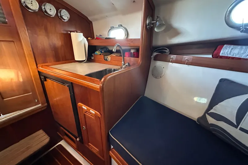 Slide: The Image of Interior of a 2008 Wasque 26 boat with wooden cabinetry and compact kitchen area. - 11