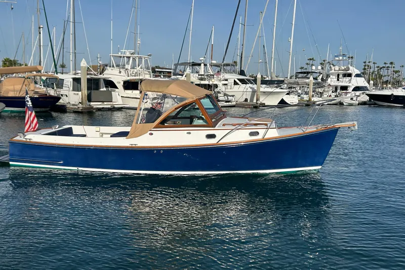 Slide: The Image of 2008 Wasque 26 boat in marina, blue hull, tan canopy, American flag displayed. - 16