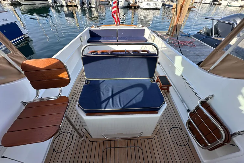 Slide: The Image of 2008 Wasque 26 boat interior with blue seating and wooden accents at a marina. - 21