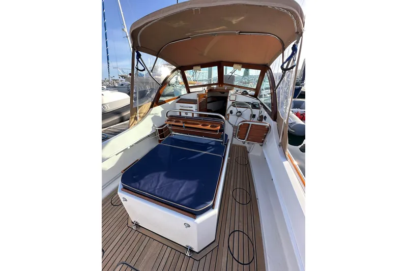 Slide: The Image of 2008 Wasque 26 boat interior with blue seating, wooden accents, and canopy in marina setting. - 22
