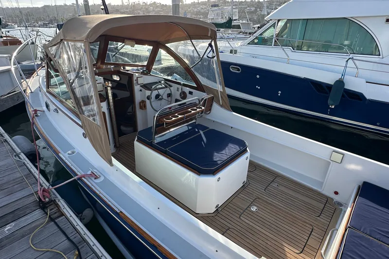Slide: The Image of 2008 Wasque 26 boat with tan canopy and blue seating, docked at marina. - 23