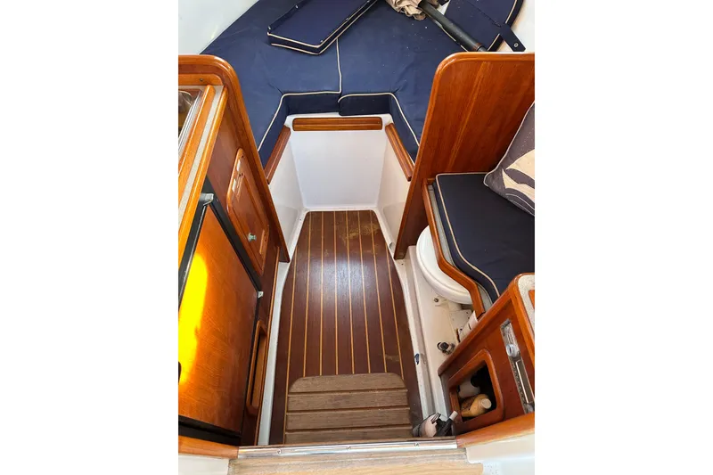 Slide: The Image of Interior of 2008 Wasque 26 boat with wooden flooring and navy cushions. - 24