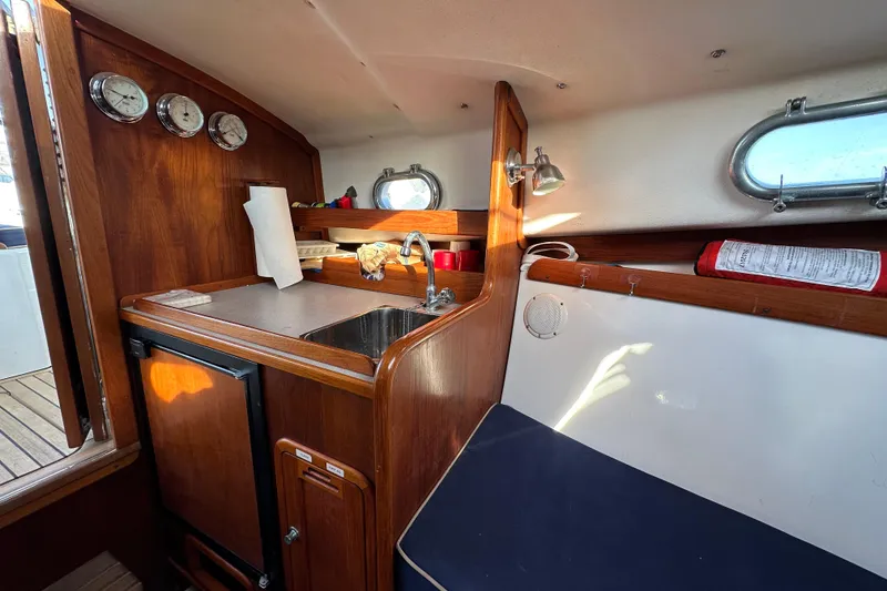 Slide: The Image of Interior of a 2008 Wasque 26 boat featuring a compact kitchenette and seating area. - 29