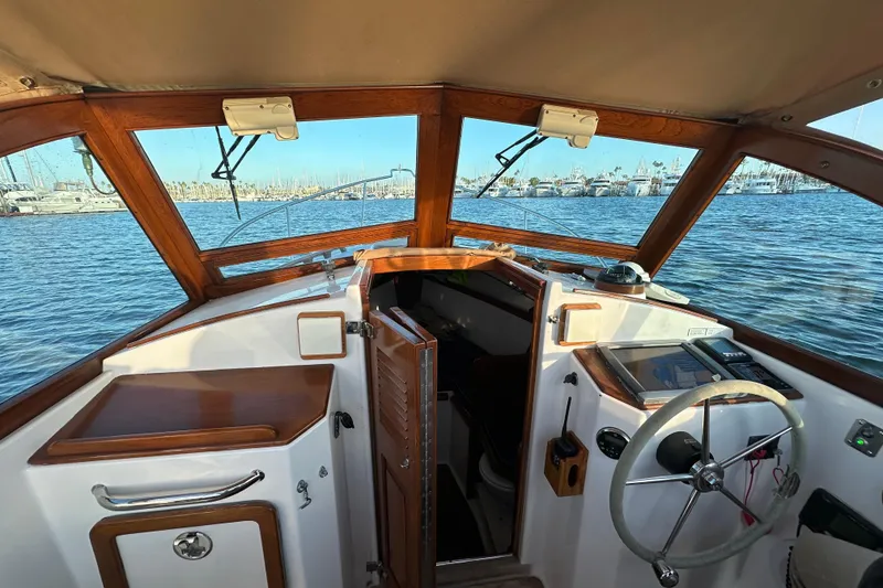 Slide: The Image of Interior view of 2008 Wasque 26 boat cockpit with wooden accents and marina background. - 3