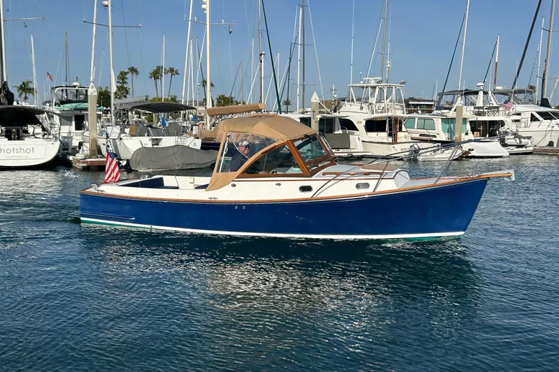 Slide: The Image of 2008 Wasque 26 boat in marina, blue hull, tan canopy, surrounded by other boats. - 37