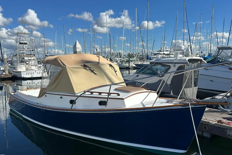 Slide: The Image of 2008 Wasque 26 boat docked in marina, blue hull, beige canopy, clear sky background. - 39