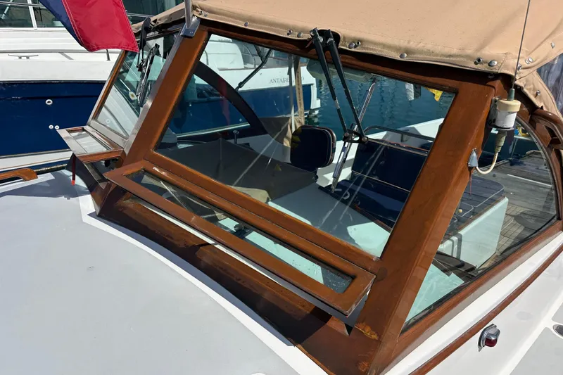 Slide: The Image of 2008 Wasque 26 boat with wooden trim and tan canopy in a marina. - 43