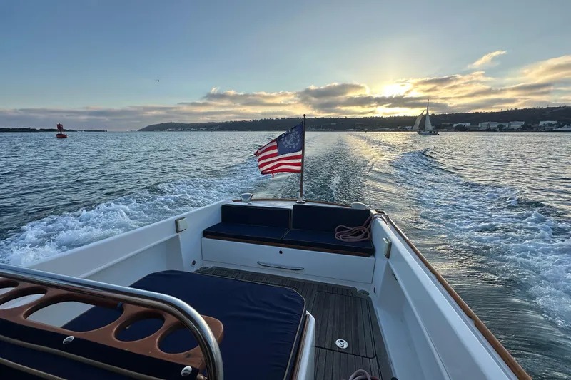 Slide: The Image of 2008 Wasque 26 boat cruising at sunset with American flag and sailboat in view. - 5