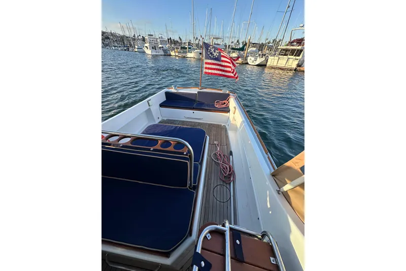 Slide: The Image of 2008 Wasque 26 boat with American flag, docked in marina, featuring blue seating. - 7