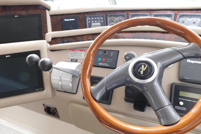 Slide: The Image of 1999 Sea Ray 500 Sundancer helm with wooden steering wheel and navigation controls. - 13