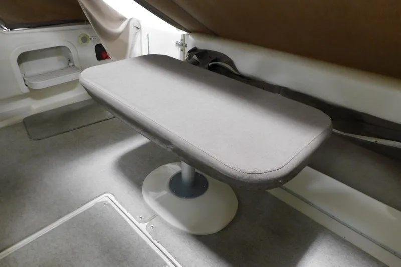 Slide: The Image of Interior table on 1999 Sea Ray 500 Sundancer yacht, featuring gray upholstery and carpeted flooring. - 36