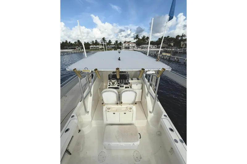 Slide: The Image of 2003 Pursuit 3070 Offshore Center Console boat docked, featuring spacious deck and helm. - 11
