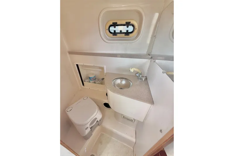 Slide: The Image of Compact bathroom in 2003 Pursuit 3070 Offshore Center Console boat with sink and toilet. - 19
