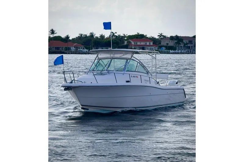 Slide: The Image of 2003 Pursuit 3070 Offshore Center Console boat on water with blue flags. - 2