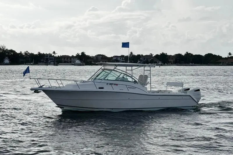Slide: The Image of 2003 Pursuit 3070 Offshore Center Console boat on calm water, with coastal background. - 3