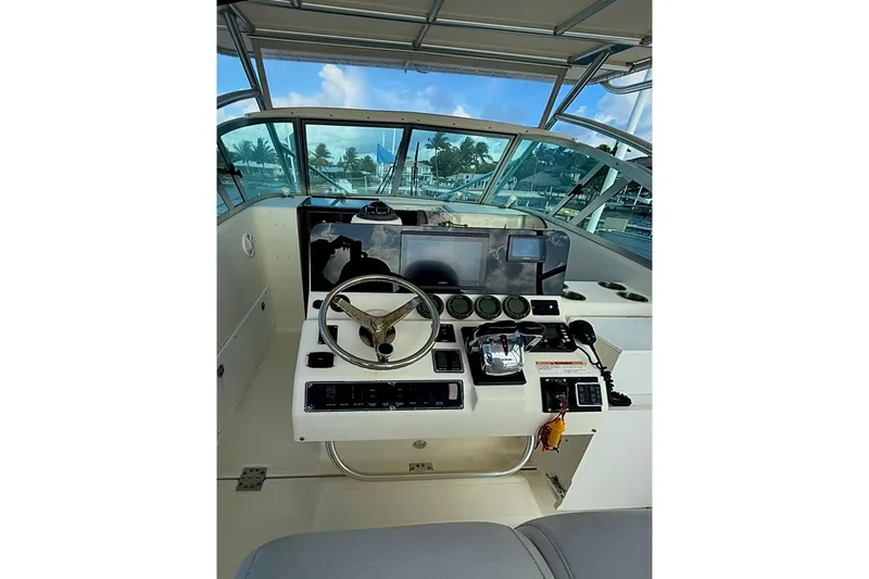 Slide: The Image of 2003 Pursuit 3070 Offshore Center Console helm with steering wheel and navigation instruments. - 7
