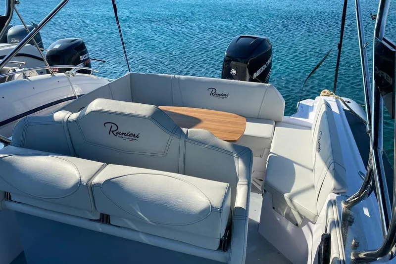 Slide: The Image of 2022 Ranieri CAYMAN 27.0 SPORT TOURING boat interior with seating and table on clear water. - 15