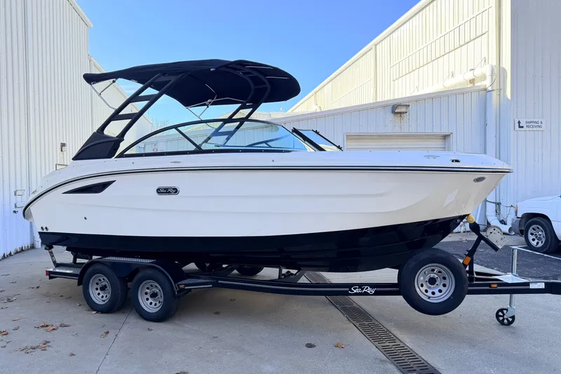 The Image of 2026 Sea Ray SDX 230 boat on trailer, parked outside a white building. - 0