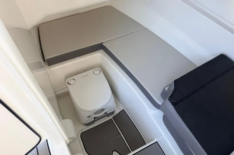 Slide: The Image of 2026 Sea Ray SDX 230 boat interior with compact toilet and cushioned seating. - 10