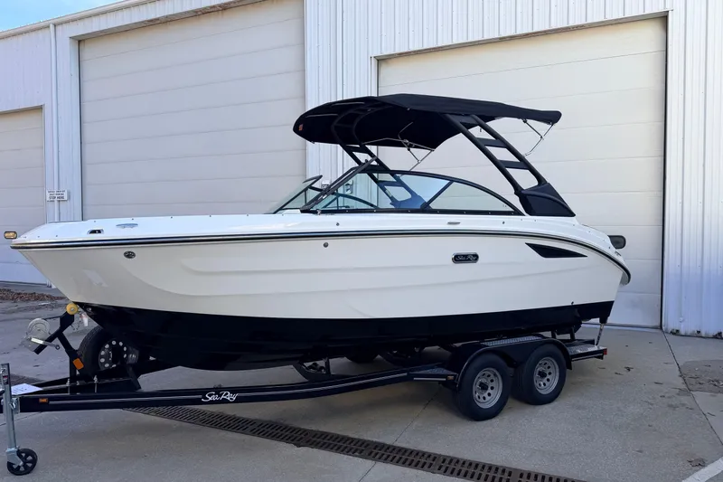 Slide: The Image of 2026 Sea Ray SDX 230 boat on trailer, parked outside a white building. - 2