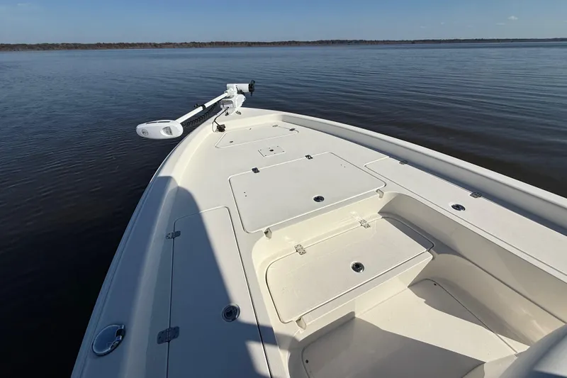 Slide: The Image of 2018 ShearWater 23LTZ boat on calm water, featuring a spacious deck and storage compartments. - 18
