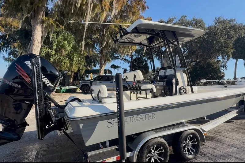Slide: The Image of 2018 ShearWater 23LTZ boat with Mercury engine on trailer, surrounded by trees. - 2
