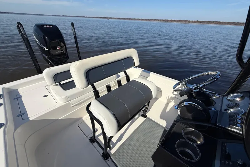 Slide: The Image of 2018 ShearWater 23LTZ boat interior with steering wheel and seating on calm water. - 26