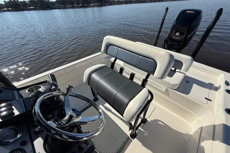 Slide: The Image of 2018 ShearWater 23LTZ boat interior with steering wheel and seating, on calm water. - 27