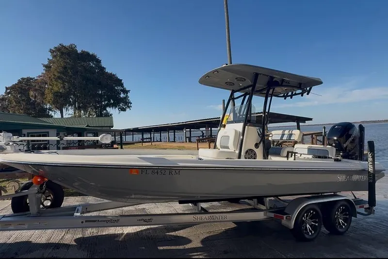 Slide: The Image of 2018 ShearWater 23LTZ boat on trailer by lakeside dock. - 3