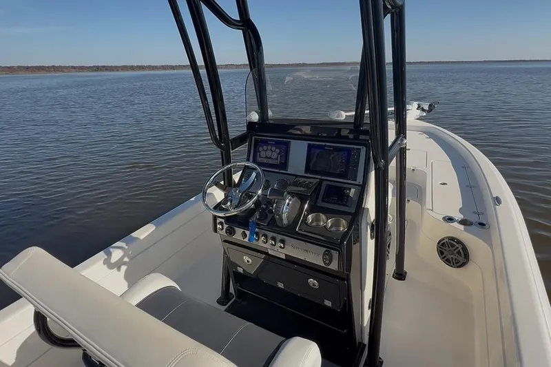 Slide: The Image of 2018 ShearWater 23LTZ boat dashboard with steering wheel and navigation controls on open water. - 6