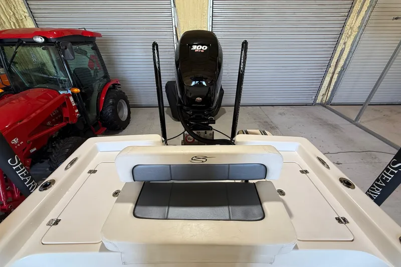 Slide: The Image of 2018 ShearWater 23LTZ boat with powerful engine, parked indoors beside red tractor. - 60
