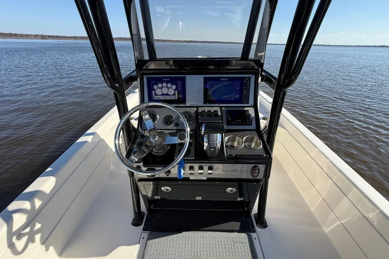 Slide: The Image of 2018 ShearWater 23LTZ boat dashboard with steering wheel and navigation screens on open water. - 8